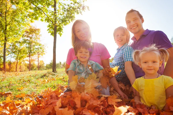 Family sitting together on leaves — Stock fotografie