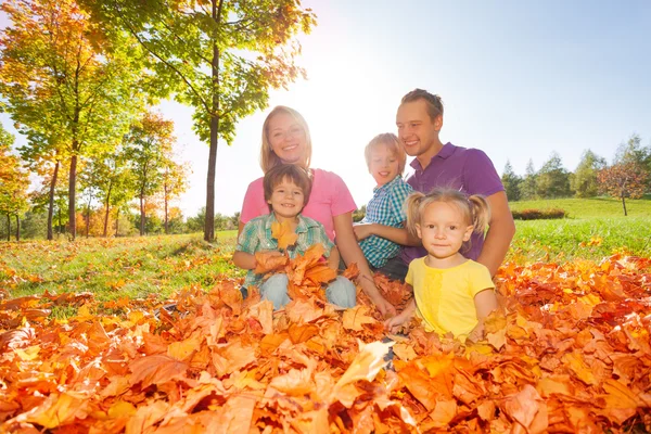Familie sitzt zusammen auf den Blättern — Stockfoto