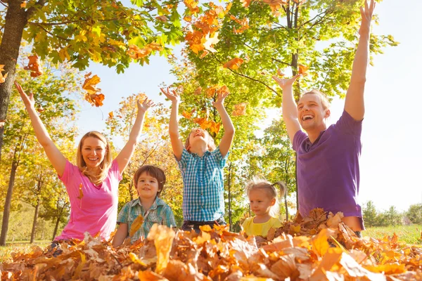 Familia jugando y lanzando hojas en el aire — Foto de Stock