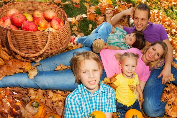 Family laying on grass with orange autumn leaves — Stockfoto