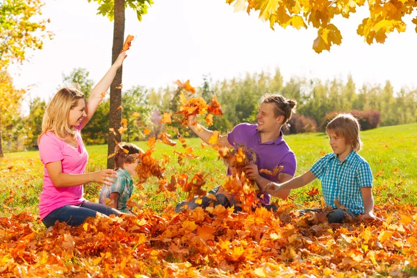 Playful kids and parents throw leaves — Stockfoto