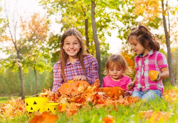 Las niñas se sientan en el parque de otoño junto con calabazas — Foto de Stock