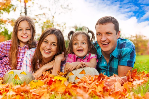 Family in autumn leaves with Halloween pumkins — Stock Photo, Image