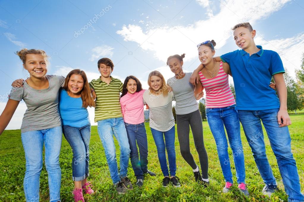 Smiling  friends standing on grass