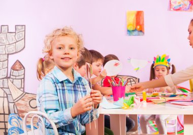 Okul öncesi sınıf sarışın çocuk oturup tablo tarafından
