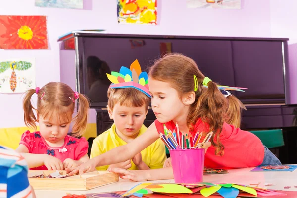 Meisje stretching voor papier in kleuterschool klasse — Stockfoto