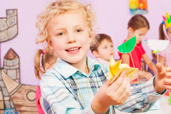 Blond handsome boy shows origami craft — Stock Photo, Image