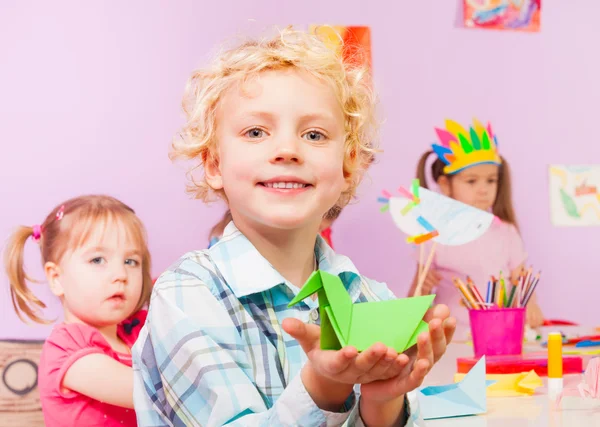 Bonito menino loiro mostra origami — Fotografia de Stock