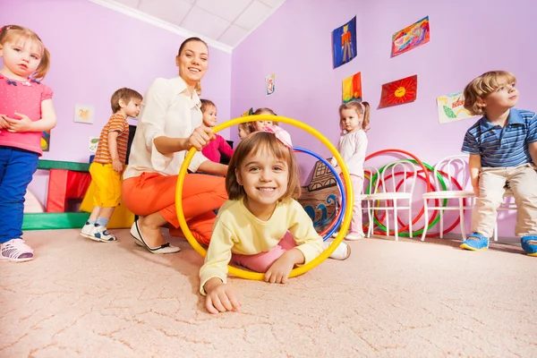 Meisje en andere kinderen kruipen hoewel hoops — Stockfoto