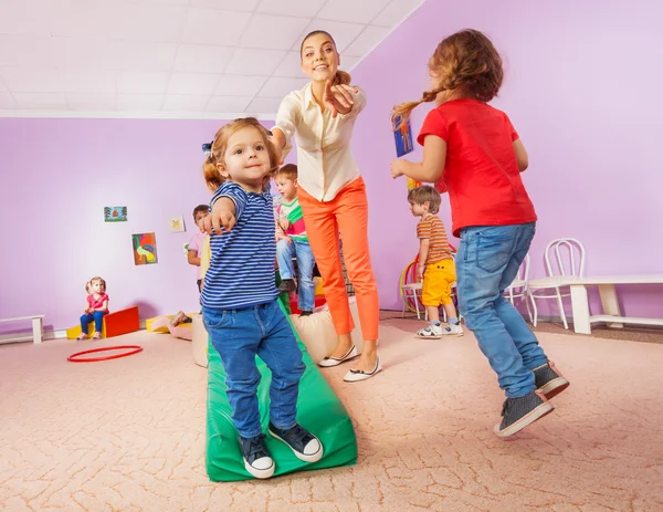 Lehrerin zeigt rennende und springende Kinder — Stockfoto