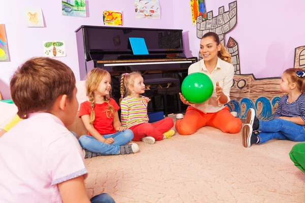 Leraar en kinderen zitten in cirkel spelen met de bal — Stockfoto