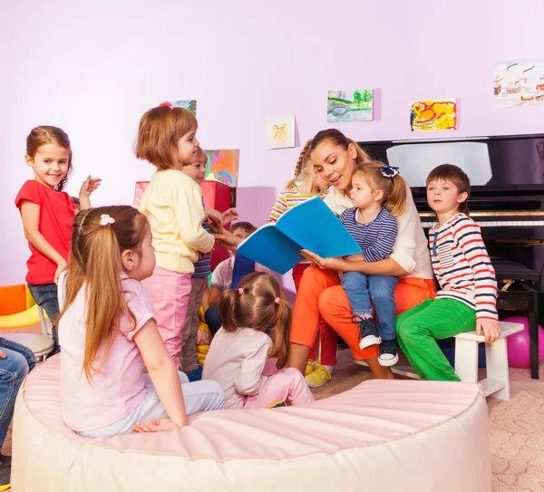 Meninos e meninas ouvem professor ler livro — Fotografia de Stock