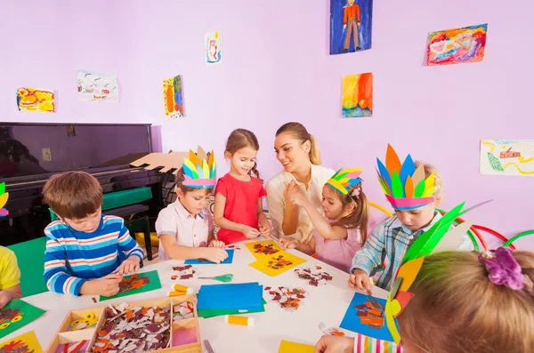 Teacher helps kids glue craft images — Stock Photo, Image