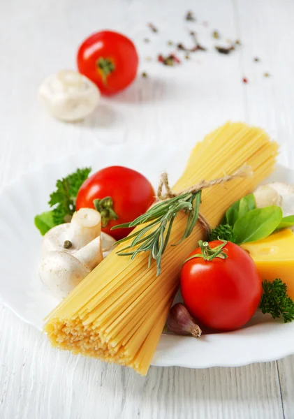 Pasta de espaguetis, queso, verduras y especias en una mesa de madera blanca . —  Fotos de Stock