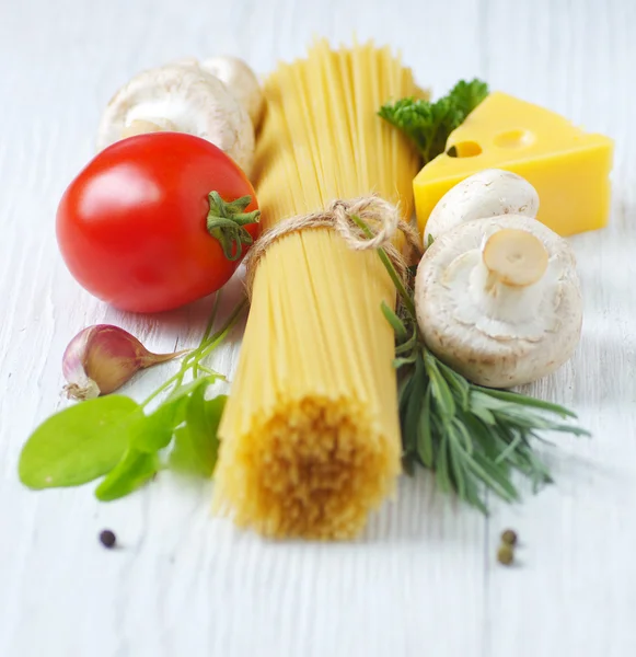 Spaghetti, ost, grönsaker och örter på en vit träbord — Stockfoto