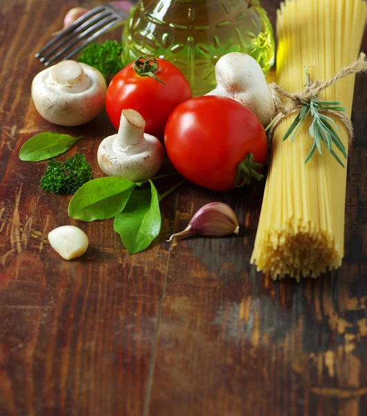 Espaguetis, tomates, champiñones y hierbas sobre una vieja mesa de madera . —  Fotos de Stock