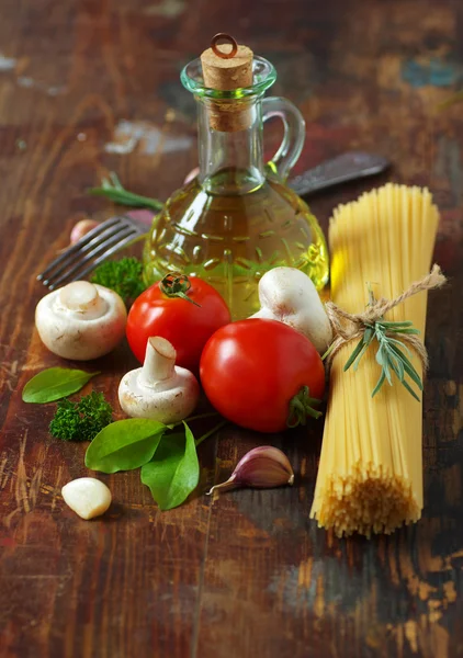 Espaguetis, tomates, champiñones y hierbas sobre una vieja mesa de madera . —  Fotos de Stock