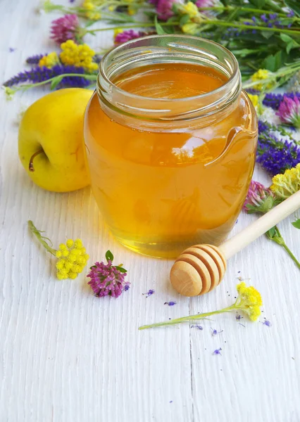 Fresh honey and wild flowers on a white wooden table. — Stock Photo, Image