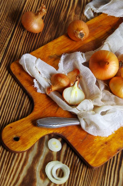 Cipolle gialle su vecchio tavolo di legno. Sfondo cucina . — Foto Stock