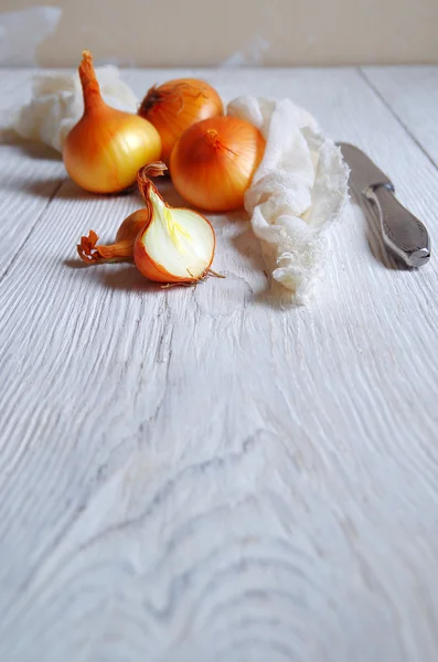 Onions on a white wooden table. — Stock Photo, Image