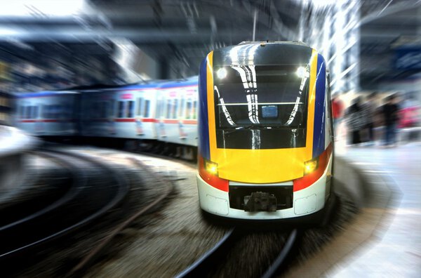Fast moving train leaving station platform with motion blur