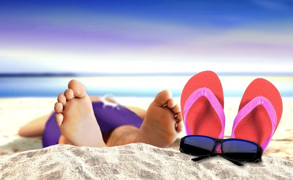 Ligger på stranden med toffel och solglasögon — Stockfoto