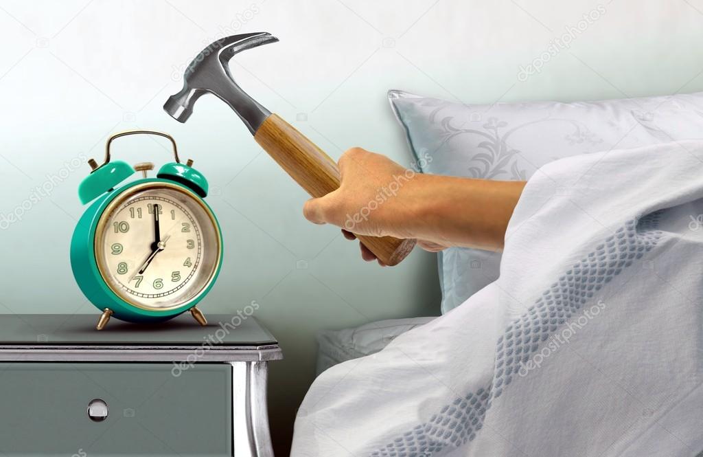 Hand hitting alarm clock with hammer
