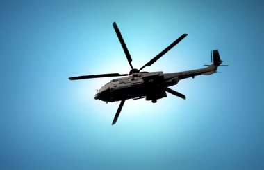 Mavi gökyüzü altında uçan askeri helikopter