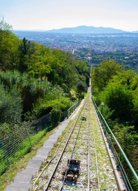 Montecatini Alto 'nun füniküler arabasından Montecatini Terme' ye doğru inen manzara. Arka planda raylar, tepeler ve Toskana doğası var..