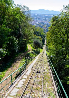 Montecatini Alto 'nun füniküler arabasından Montecatini Terme' ye doğru inen manzara. Arka planda raylar, tepeler ve Toskana doğası var..