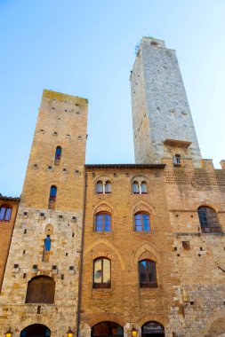Güneşli bir günde açık mavi gökyüzü altında Ortaçağ taş kuleleri ve San Gimignano, Toskana, İtalya 'daki eski binaların manzarası.