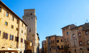 Güneşli bir günde açık mavi gökyüzü altında Ortaçağ taş kuleleri ve San Gimignano, Toskana, İtalya 'daki eski binaların manzarası.