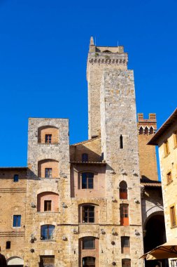 Güneşli bir günde açık mavi gökyüzü altında Ortaçağ taş kuleleri ve San Gimignano, Toskana, İtalya 'daki eski binaların manzarası.