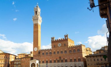 Orta çağ kulesi ve tarihi tuğla saray dar eski binalar arasında, mavi gökyüzünün altında büyüleyici bir Avrupa şehrinde bulutlar altında.