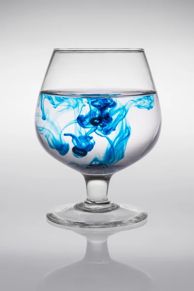 Kaca dengan tinta biru yang menciptakan gelombang warna — Stok Foto