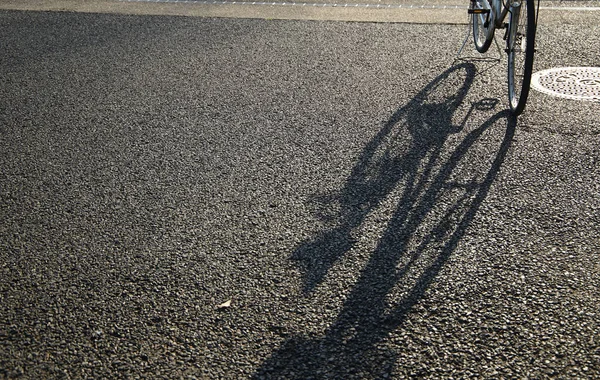 夕日に照らされた地面に映る自転車の影 — ストック写真