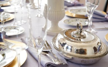 Gümüş takımlar ve cam eşyalar masanın üstünde.                               