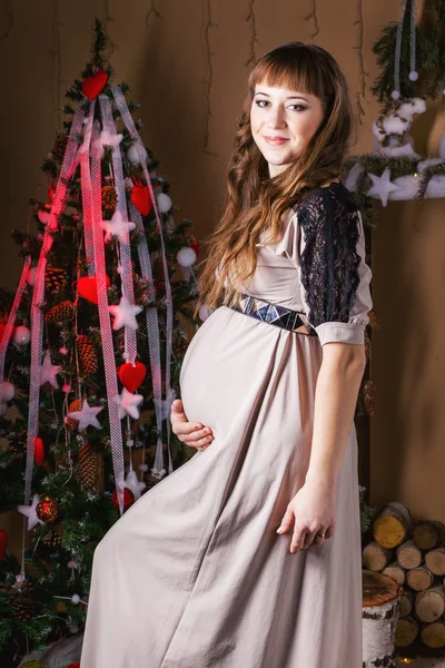 Mladá krásná těhotná žena v dlouhých šatech nedaleko nový rok tr — Stock fotografie