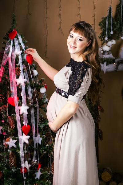 Young beautiful pregnant woman in a long  dress near new year tr — Stock Photo, Image