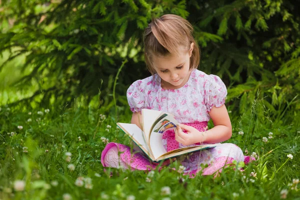 Flickan är att läsa på gräset — Stockfoto