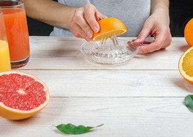 Genç bir kadın manuel cam sıkacağı kullanarak portakal suyu sıkıyor..