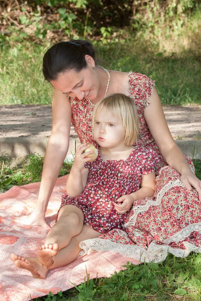 Mother with a smile looks at the reflected daughter holding appl — Stock Photo, Image