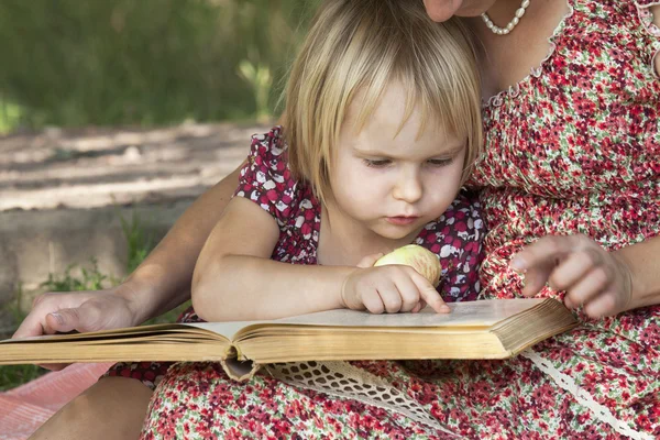 Κορίτσι, διαβάζοντας ένα βιβλίο στην αγκαλιά της μητέρας του Royalty Free Εικόνες Αρχείου