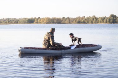 Tekne gölün ortasındaki bir köpek ile avcı