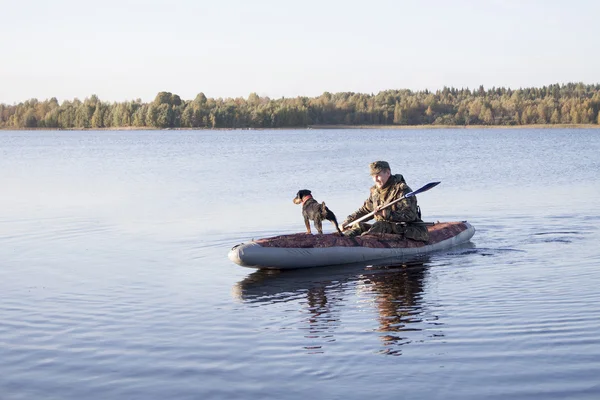 The hunter with a dog float home — Stock Photo, Image