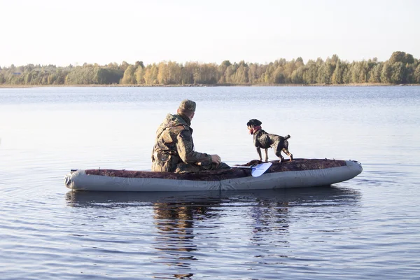 The hunter with a dog in the boat in the middle of the lake — Stock Photo, Image