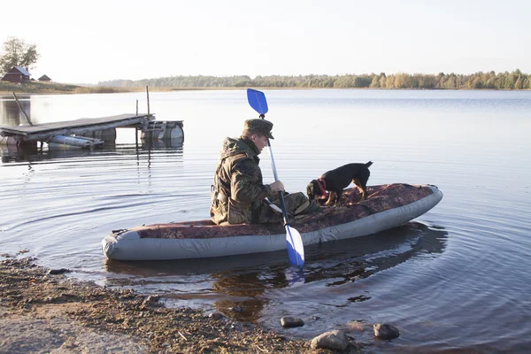 The hunter with a dog in an inflatable boat sail on hunting — Stock Photo, Image