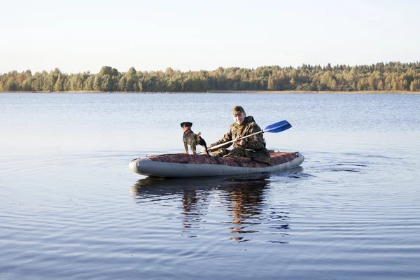 The hunter and hunting dog float on the lake after duck hunting — Stock Photo, Image