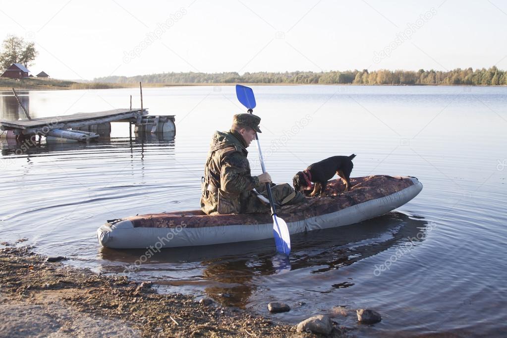 The hunter with a dog in an inflatable boat sail on hunting