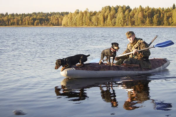 The hunter floats in the boat with two dogs — Stock Photo, Image